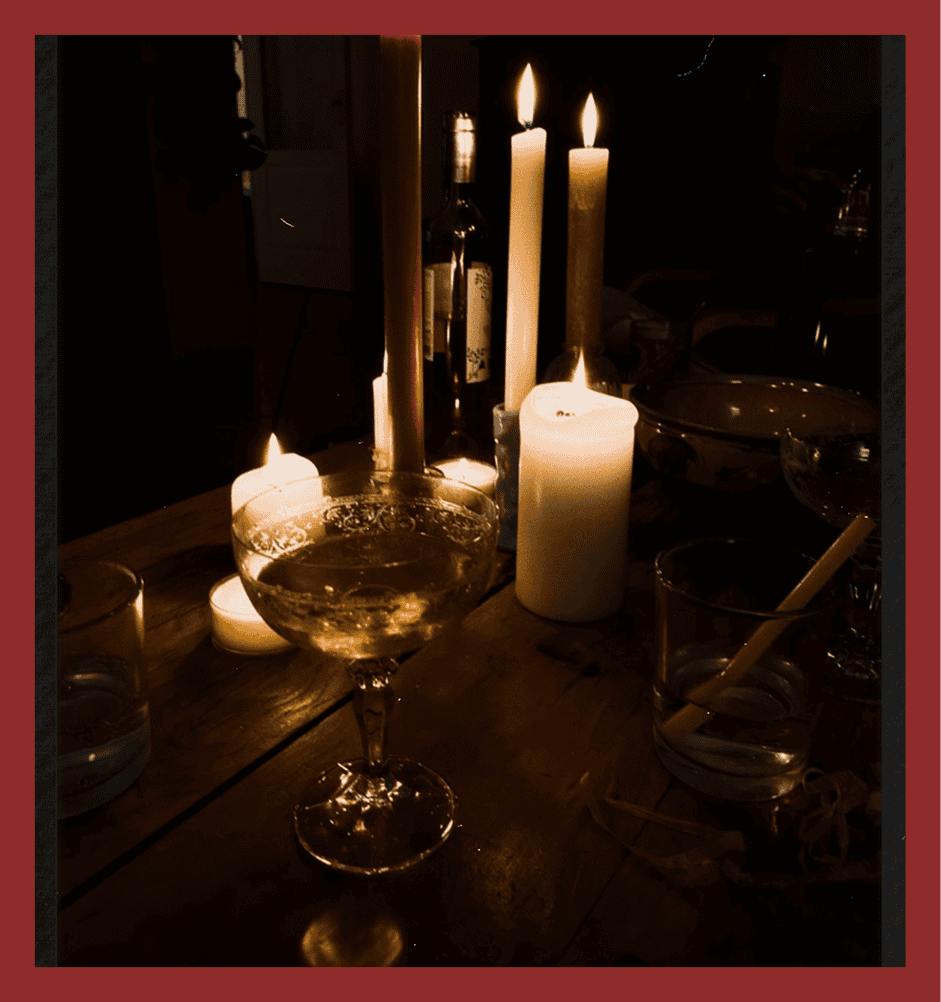 Intimate dining scene with candles, wine glass, and warm lighting atmosphere.