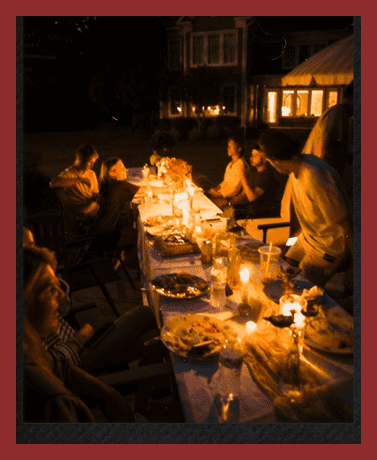 Outdoor dinner party with friends, candles, and festive food, featuring vanalondon.com event services.