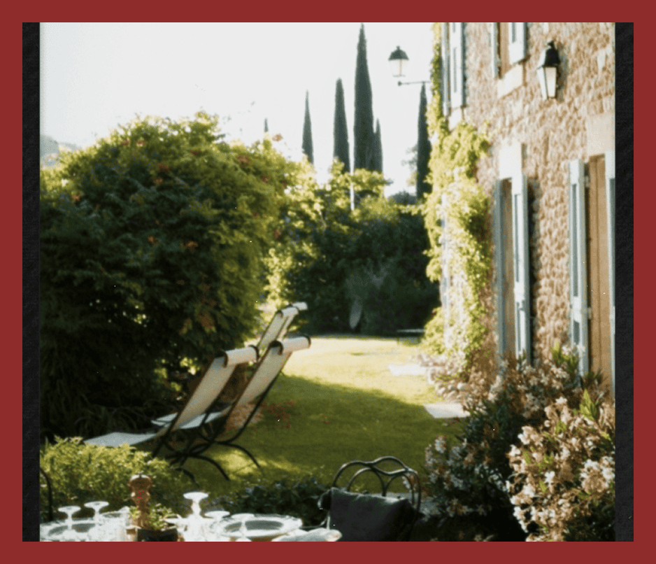 Beautiful outdoor garden with lush greenery, cozy seating, and classic European architecture.