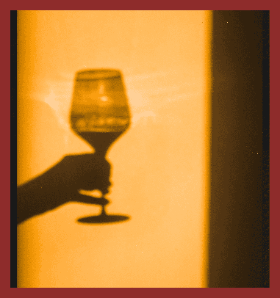 Silhouette of a wine glass hand shadow against warm background, ideal for elegant event themes.
