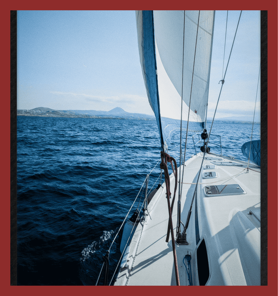 Sailboat on open blue sea with distant islands under clear sky. Perfect for sailing trips and maritime leisure.