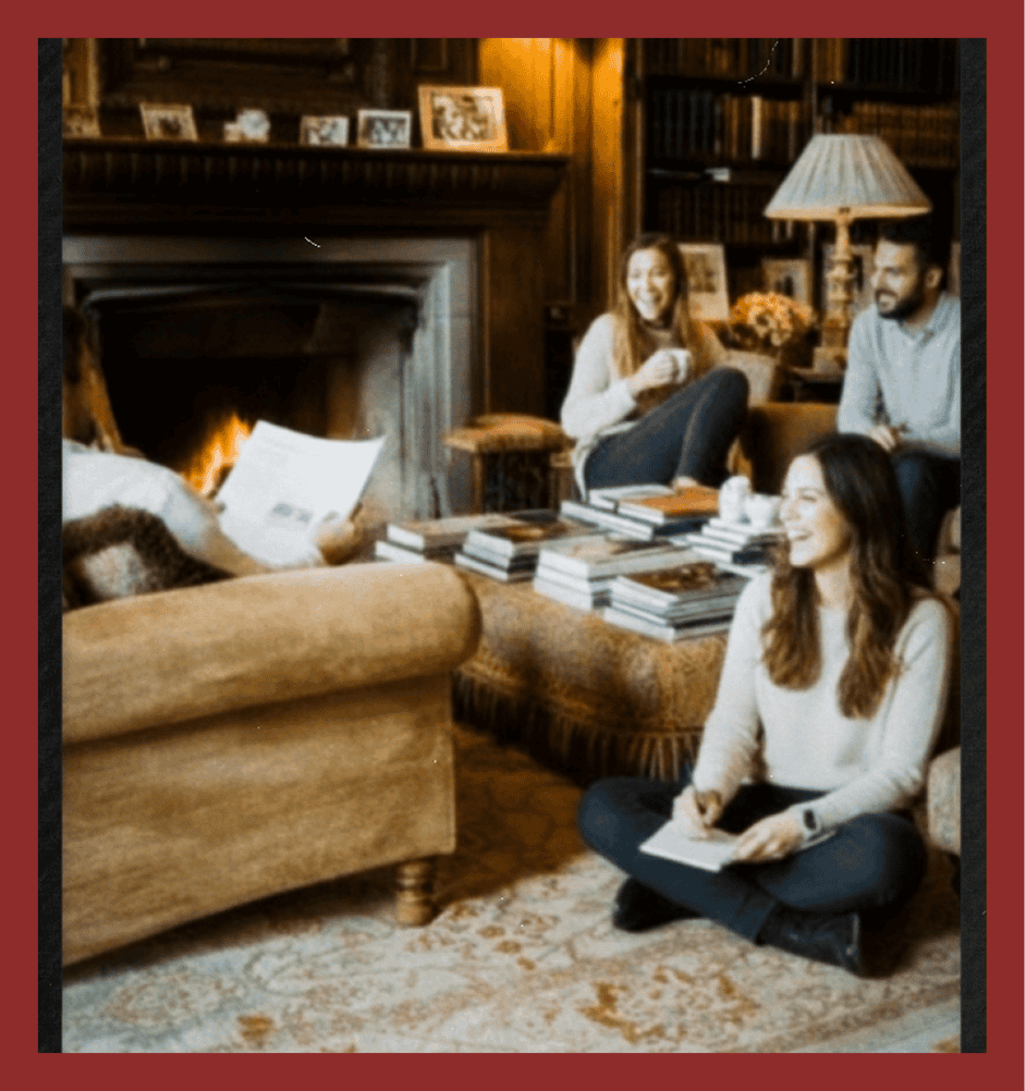Friends enjoying reading discussion by fireplace in warm living room.