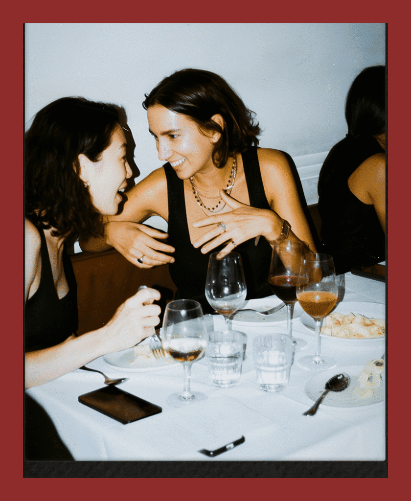 Women relishing conversation at a restaurant table with wine.
