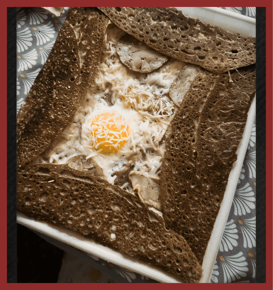 Delicious buckwheat galettes filled with melted cheese, a sunny-side-up egg, and mushrooms, served o.