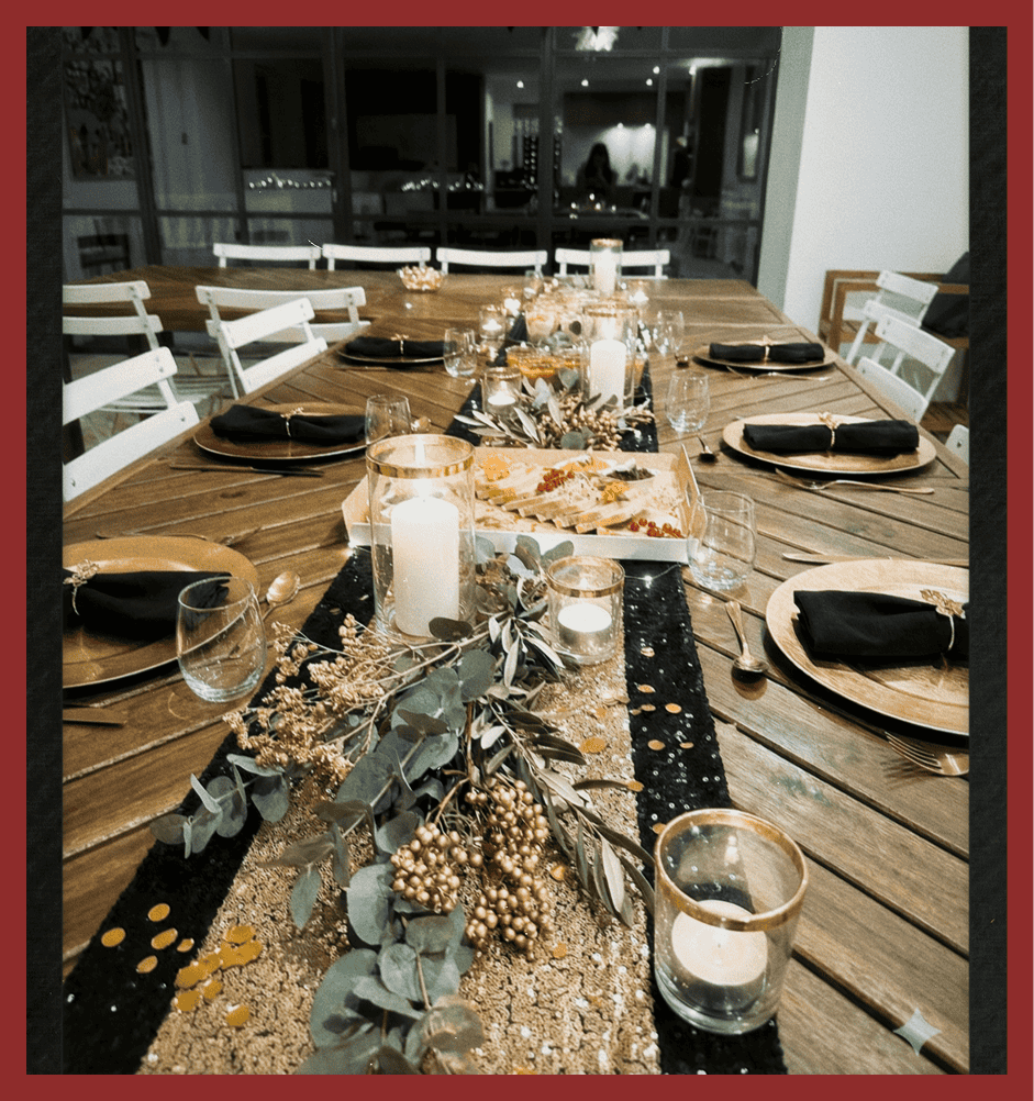 Elegant dinner table setup with candles, black napkins, and rustic decor for special occasions.