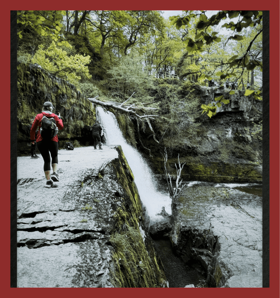 Freshwater waterfall with hikers on a scenic trail.