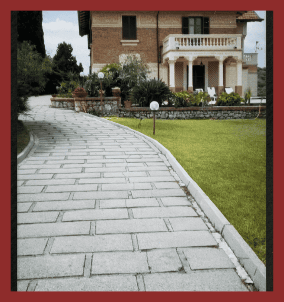 Beautiful stone-paved driveway leading to a luxurious house with garden.