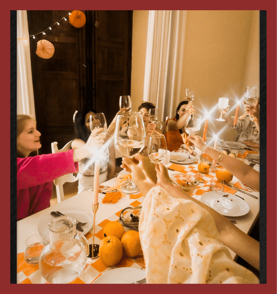 A joyful group toasting wine glasses at a stylish dinner party.